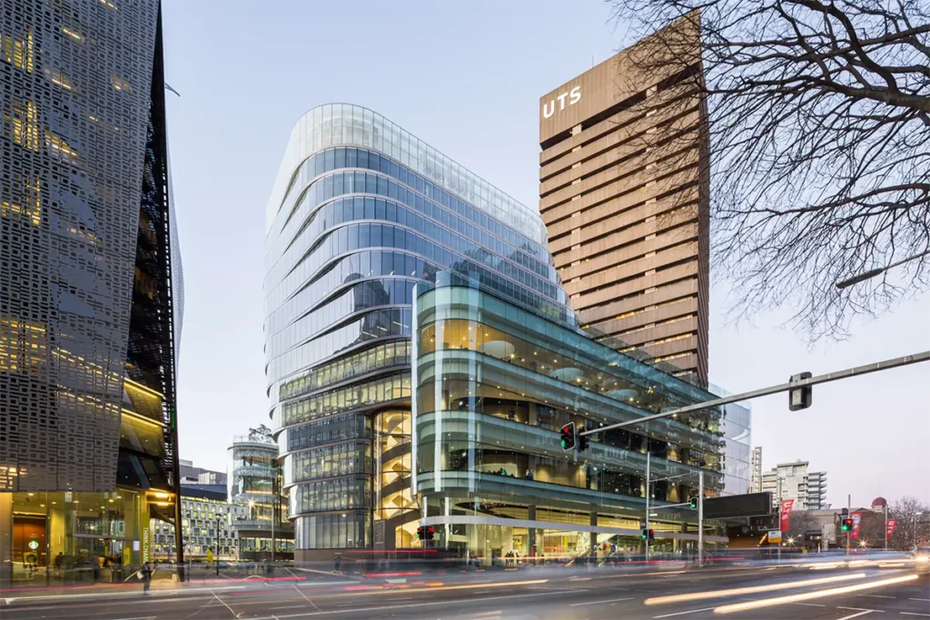 Bâtiments modernes en verre de l'UTS illuminés au crépuscule, au carrefour animé du centre-ville de Sydney